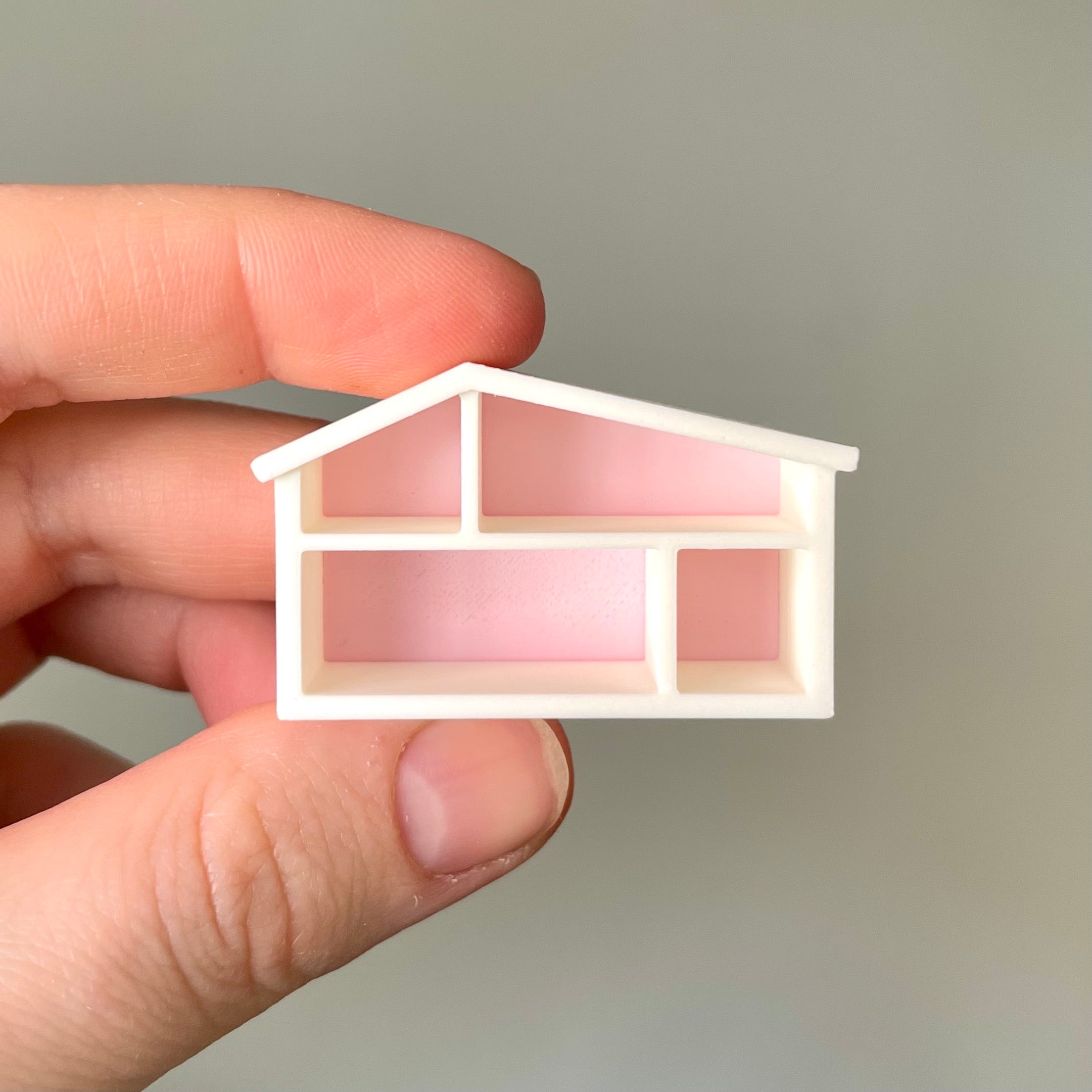 Miniatyr dockhus som ser ut som en mini-version av Lundbys dockskåp, i vitt och rosa